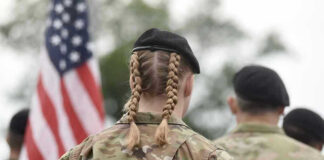 Soldier with braided hair in uniform, American flag visible.