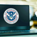 MASSIVE OVERPAYMENT? Warehouse DEALS Under FIRE Laptop displaying U.S. Department of Homeland Security logo.
