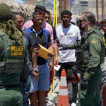 Border Sparks FURY: Controversy Escalates Border patrol agents inspecting group of individuals in line.