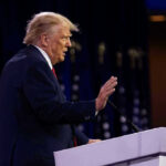 Trump’s ‘EXPLOSIVE’ 2026 Plot Unveiled Person speaking at a podium with hand raised
