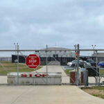 ICE Scandal–QUESTIONABLE Death DISCOVERED Chain-link fence with Restricted Area Stop No Photography sign.