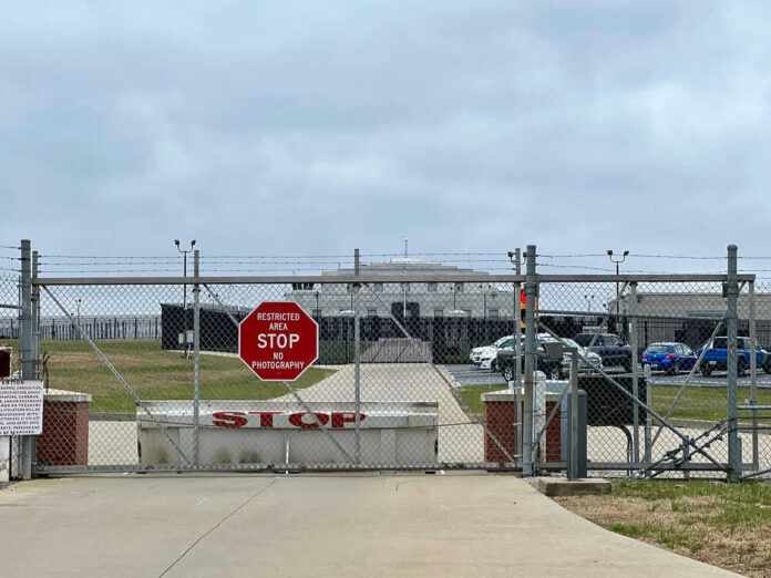 Chain-link fence with Restricted Area Stop No Photography sign.