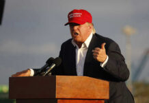 Trump TIGHTENS Housing Rules—WHO’S OUT? Person speaking at a podium wearing a red hat.
