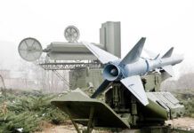 Military missile launcher with radar systems in a foggy field.
