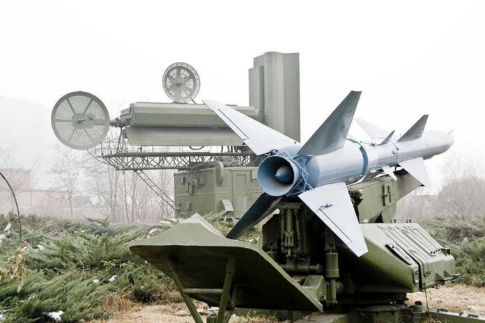 Military missile launcher with radar systems in a foggy field.