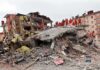 Dorm Strike HORROR: Many Dead, More Missing Rescue workers in orange uniforms on a collapsed building site after an earthquake