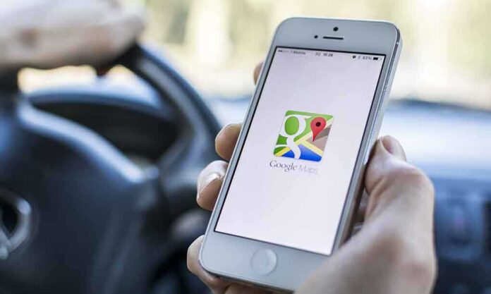 shutterstock_176093684-1 A person holding a smartphone displaying the Google Maps app while driving