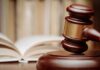 A wooden gavel resting on a sound block with law books in the background