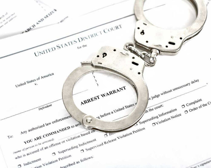 1316784506 Handcuffs on top of an arrest warrant document.