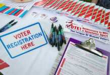 California Eyes Lower Billionaire Tax to Fund Healthcare Voter registration table with forms, pens, and brochures.