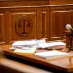 Wooden courtroom desk with papers and a microphone.