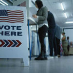 Federal Agents Confront Poll Worker During Election Sign reading Vote Here in a polling station.