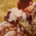 Officer’s Film Forces Attention on Military Sexual Trauma Crisis Soldier sitting, leaning head on helmet.