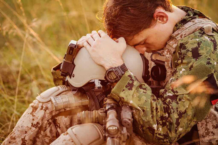 Soldier sitting, leaning head on helmet.