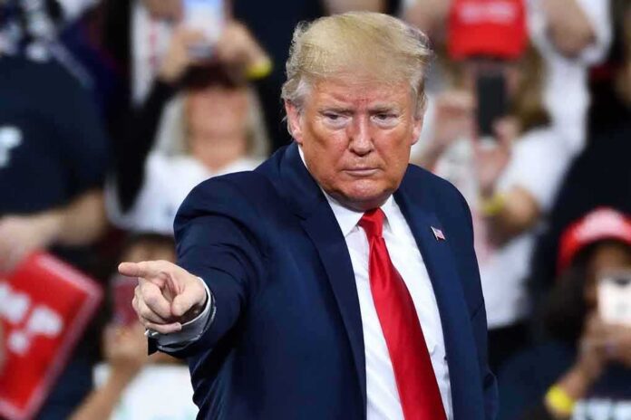 A man in a suit pointing during a speech at a rally