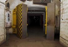 Entrance to an underground bunker with large heavy doors and a sign