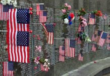 Memorial Backlash Explodes on the Mall Memorial wall adorned with American flags and flowers