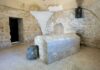 Interior of a historical site featuring a stone tomb and ancient walls