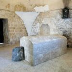 Interior of a historical site featuring a stone tomb and ancient walls