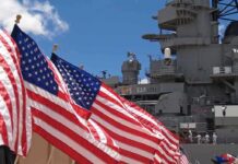 Congress Moves to Cut Battleship Plan American flags in front of a naval ship under a blue sky