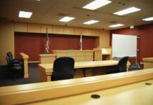 Massachusetts Welfare Sting Explodes Interior view of an empty courtroom with wooden furniture and American flags
