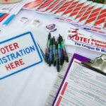 California’s Election Showdown Takes Center Stage This July 4 Voter registration table with forms, pens, and brochures.