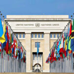 Global Conflicts Escalate, Nuclear Nonproliferation System Faces New Strains United Nations building with numerous national flags outside.