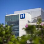 New Jersey Heat Crisis: 19 Lives Lost Modern hospital building with a prominent H sign against a clear blue sky