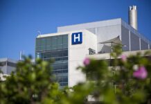 New Jersey Heat Crisis: 19 Lives Lost Modern hospital building with a prominent H sign against a clear blue sky