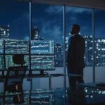 Trader in a dark office with multiple stock monitors and city skyline at night