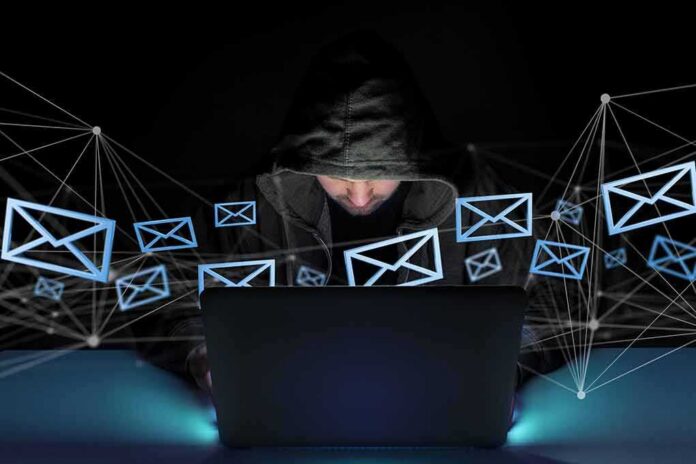 shutterstock_1013607241 Hooded person using a laptop surrounded by email icons