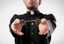 Pastor Gets Life for Child Rape Person in black robe holding handcuffs forward