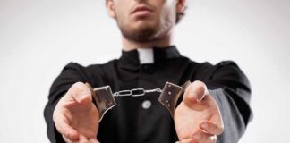 Person in black robe holding handcuffs forward