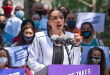 NYC Mayor Mourns Rikers Detainee Woman speaking at outdoor rally behind microphones