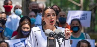Woman speaking at outdoor rally behind microphones