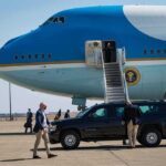 U.S.-Russia Talks Move Behind the Scenes Security detail near blue and white aircraft with staircase and SUV