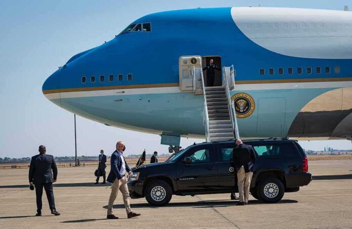 Security detail near blue and white aircraft with staircase and SUV