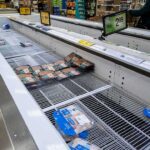 supermarket freezer with mostly empty shelves and a few meat packages