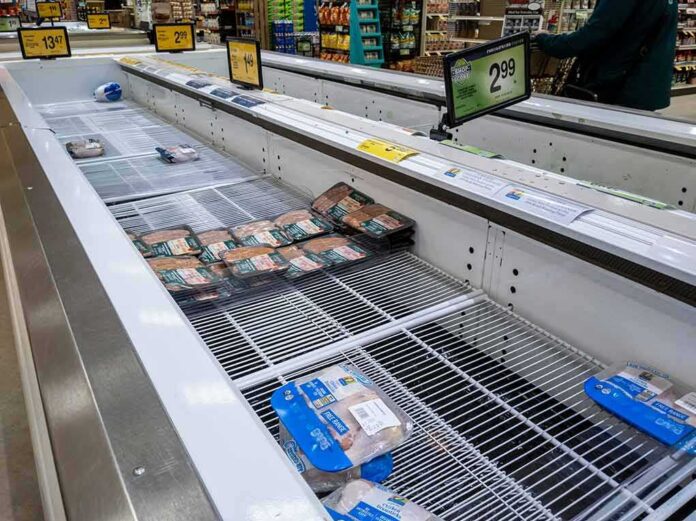 supermarket freezer with mostly empty shelves and a few meat packages
