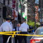 Police officers and investigators at a taped-off city street scene