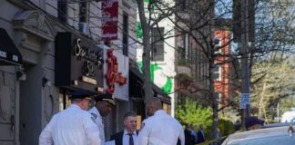 Police officers and investigators at a taped-off city street scene