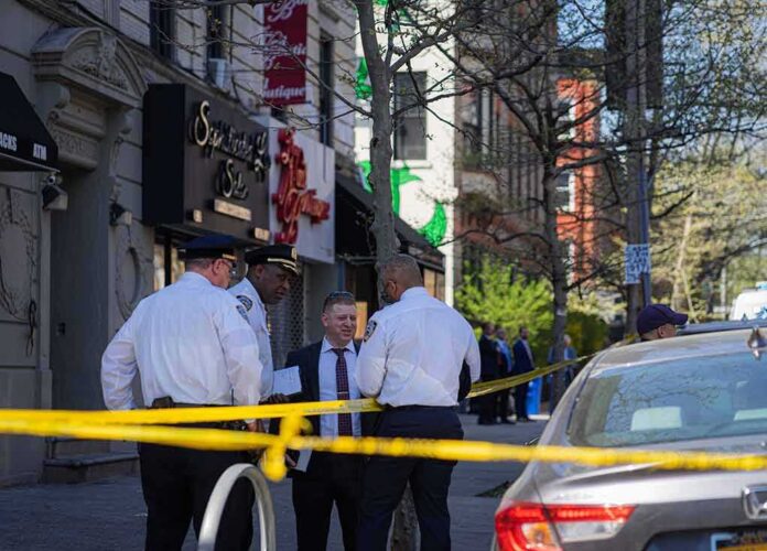 Police officers and investigators at a taped-off city street scene