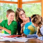 Teacher with two children studying a globe at a table