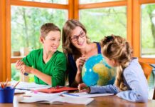 Teacher with two children studying a globe at a table