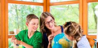 Teacher with two children studying a globe at a table