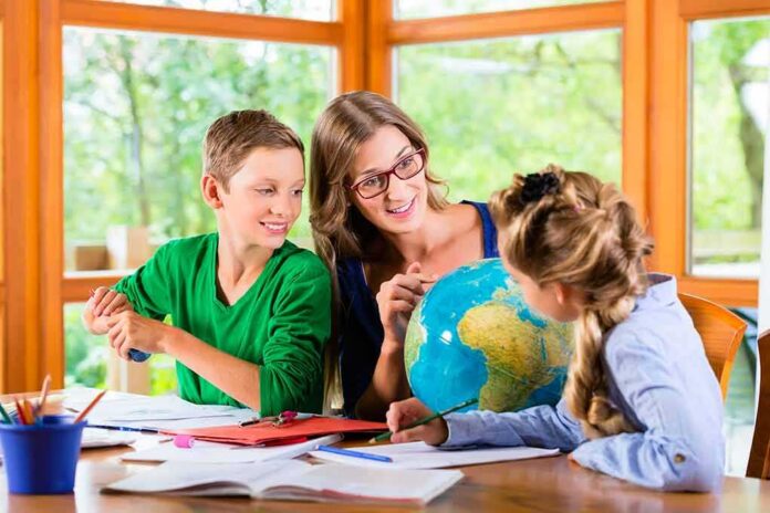 shutterstock_311682371 Teacher with two children studying a globe at a table