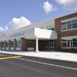Villages Fear Migrant Housing Plan Near Schools Modern school building with large windows and a clear sky