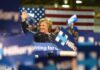 Senate Race Ignites Debate Over El-Sayed’s Allies woman waving at a rally podium