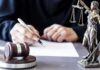 Judge Rules KSM Confession Was Involuntary Judge writing at desk with gavel and Lady Justice statue