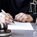 Judge Rules KSM Confession Was Involuntary Judge writing at desk with gavel and Lady Justice statue